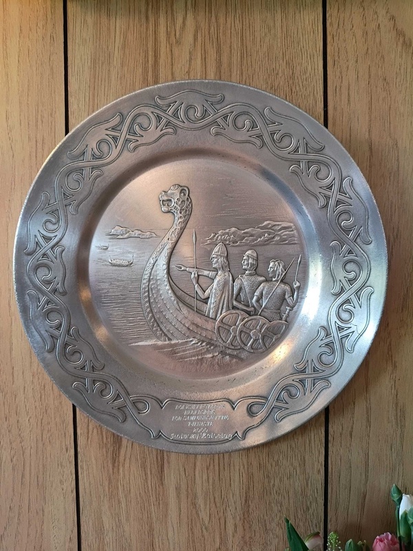 Decorative, circular pewter plate featuring a Viking longship and Norse warriors